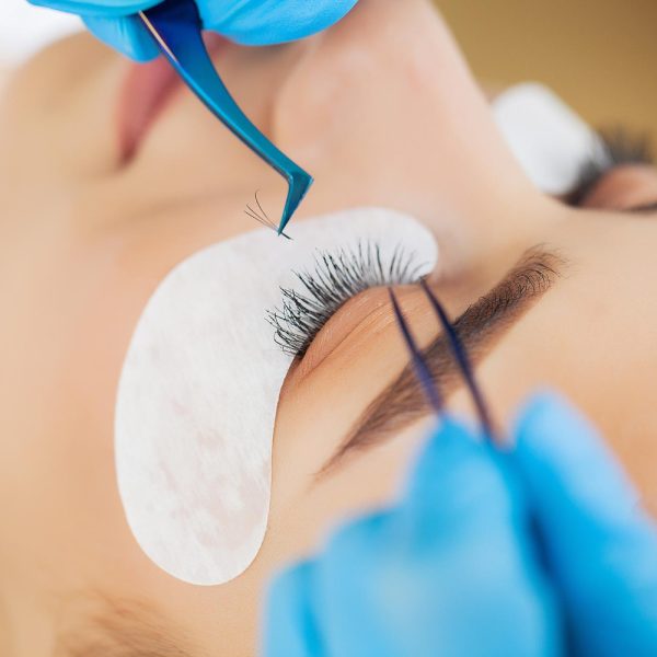 closeup-master-of-eyelash-extensions-extends-eyelashes-to-a-beautiful-woman